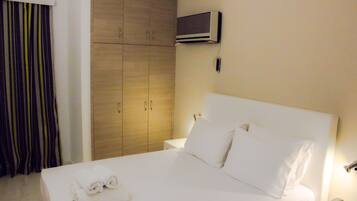 A hotel room with a bed, a wardrobe, a TV, and a telephone.