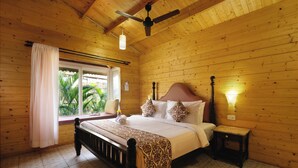 A wooden room with a bed, a nightstand, a window with curtains, and a ceiling fan.