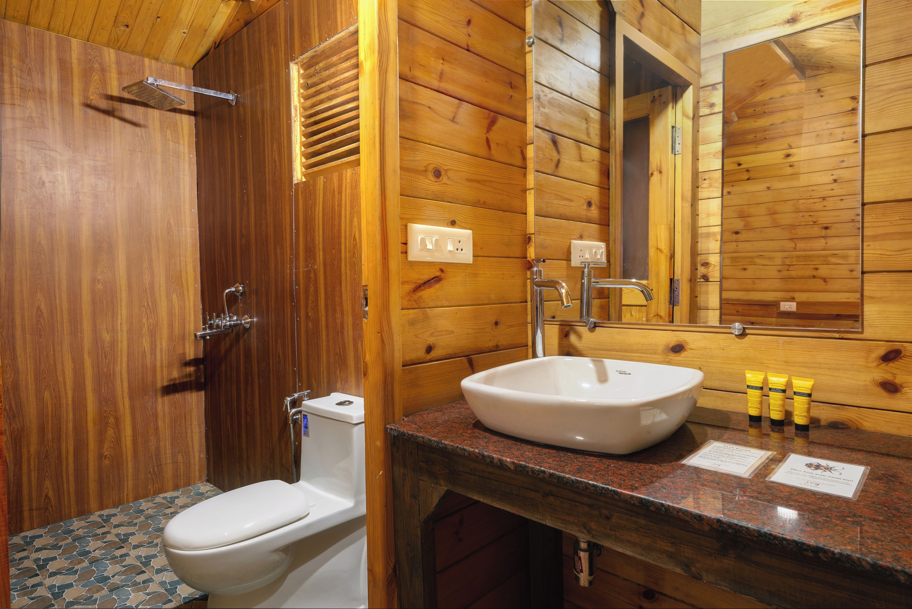 Een houten badkamer met toilet, wastafel en spiegel.