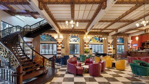 A lobby with a checkered floor, a staircase, and colorful seating areas. - Orange County Kemer (Kemer)
