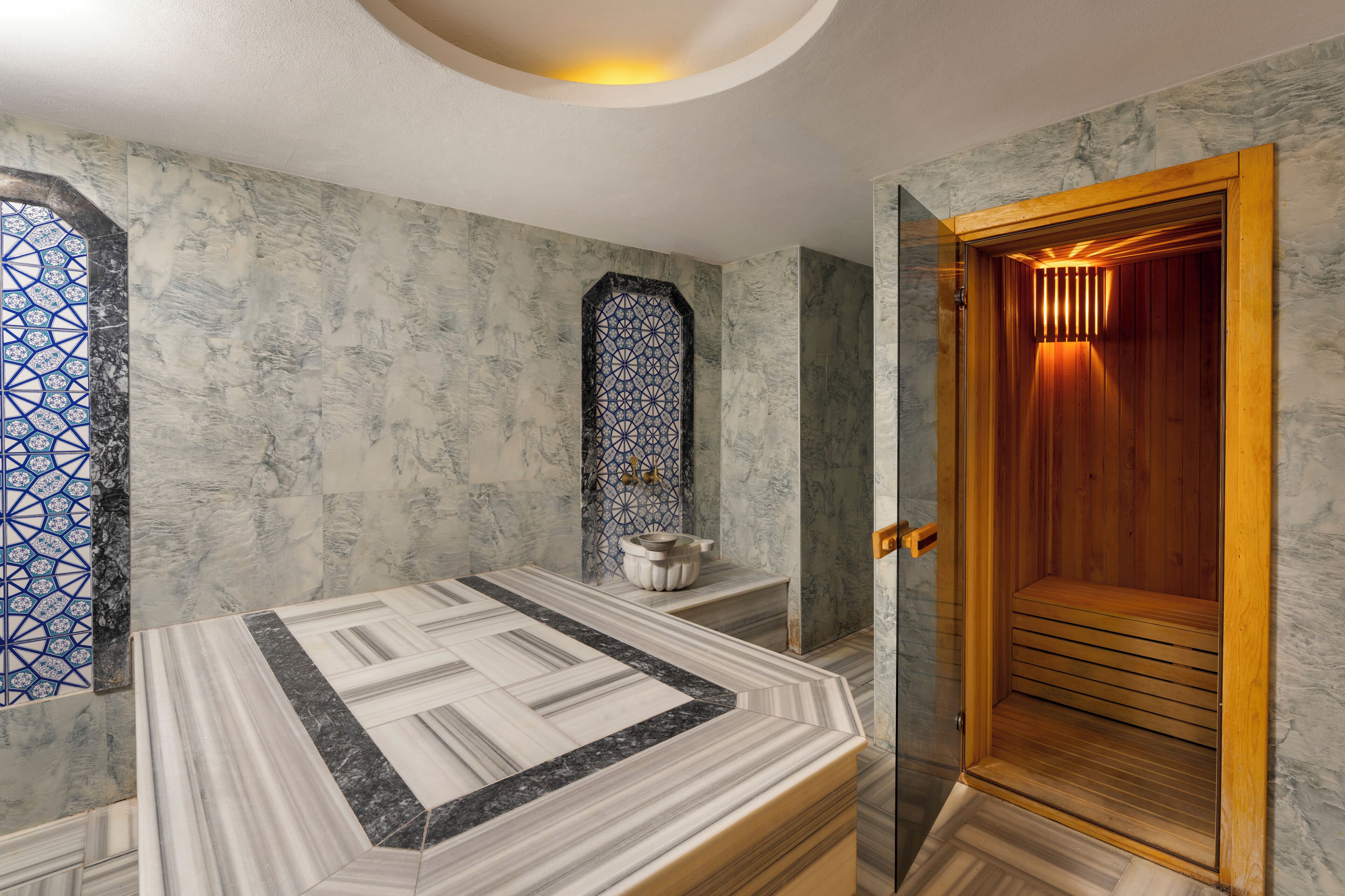 Ein Badezimmer mit Marmorboden, Holztür und Wandverkleidung mit Muster.