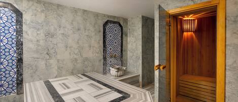 A bathroom with a marble floor, a wooden door, and a patterned wall.