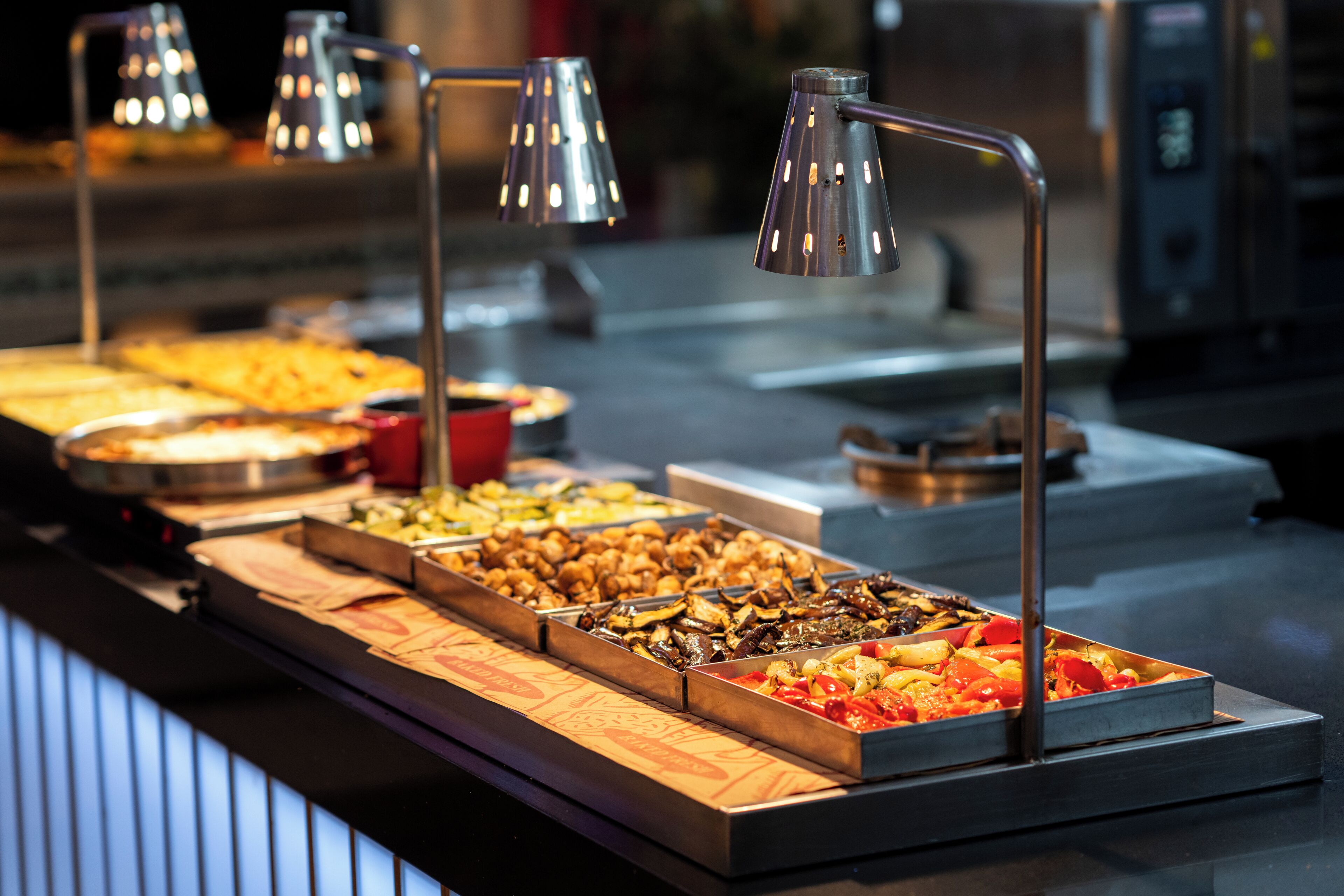 A buffet with various food items and metal lamps.