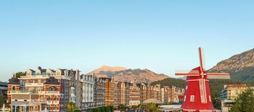 Un molino rojo en un pueblo con edificios históricos y montañas al fondo.