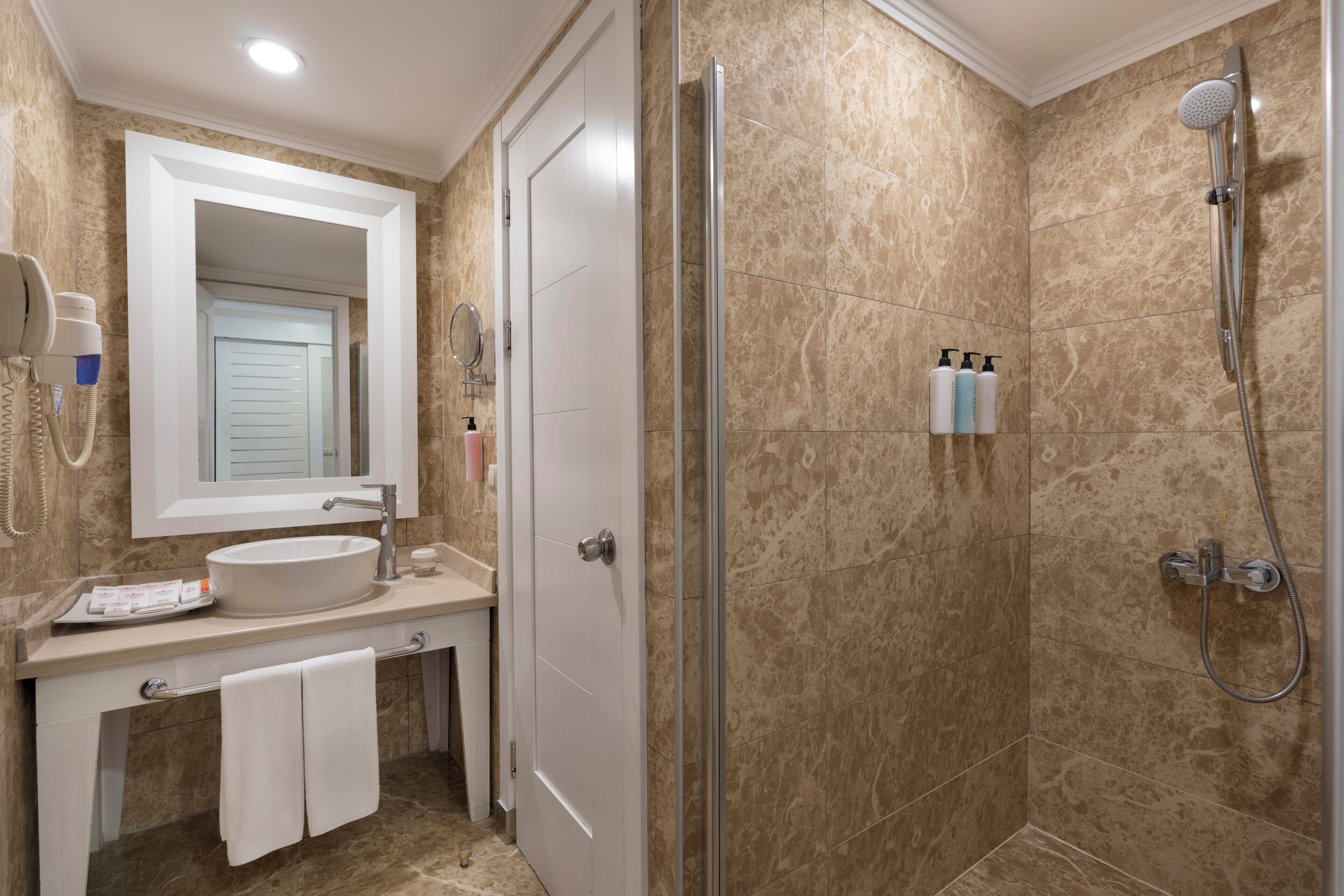 Ein Badezimmer mit Waschbecken, Spiegel, Handtuchhalter und Dusche.