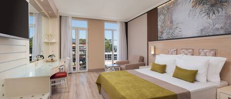 Habitación de hotel con cama, escritorio, silla, televisor y balcón con vistas.