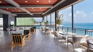 A spacious outdoor lounge area with multiple seating arrangements, a large screen, and a view of the sea. - Orange County Kemer (Kemer)