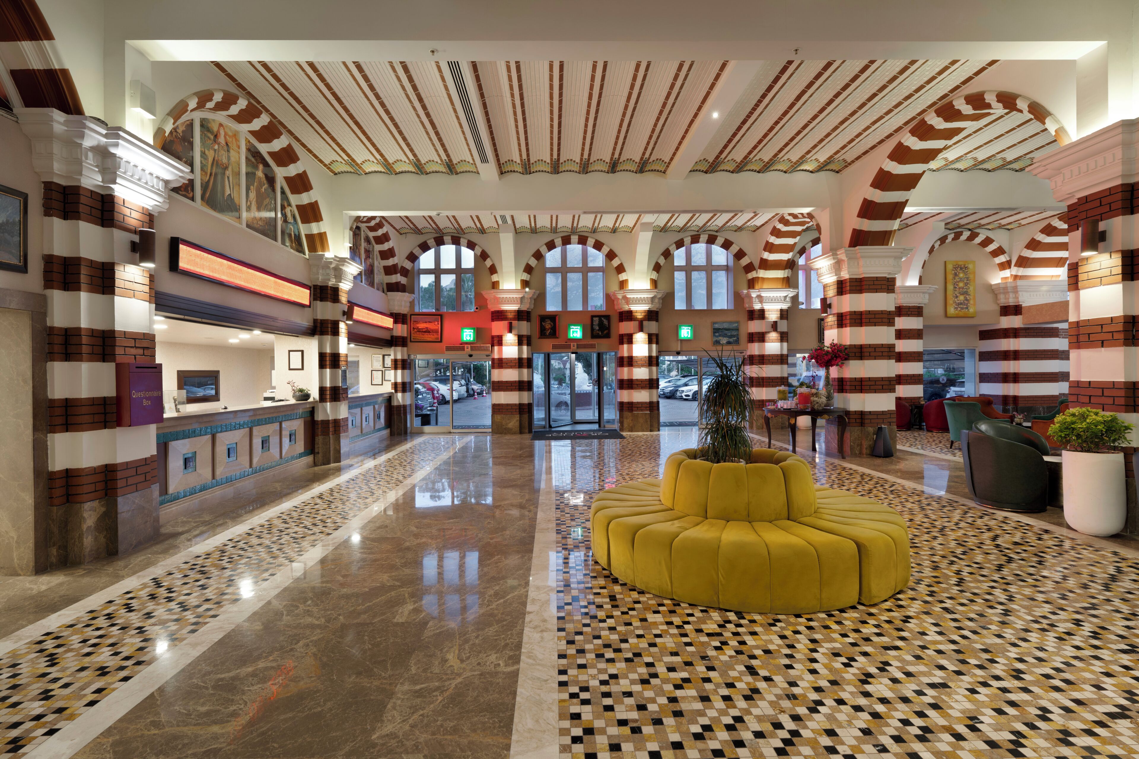 A lobby with a check-in counter, a yellow seating area, and a tiled floor.