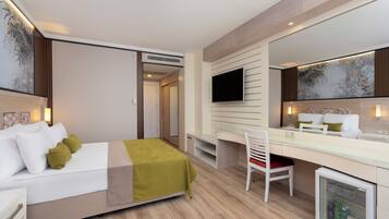Una habitación de hotel moderna con cama, escritorio, silla, televisor y mini refrigerador.