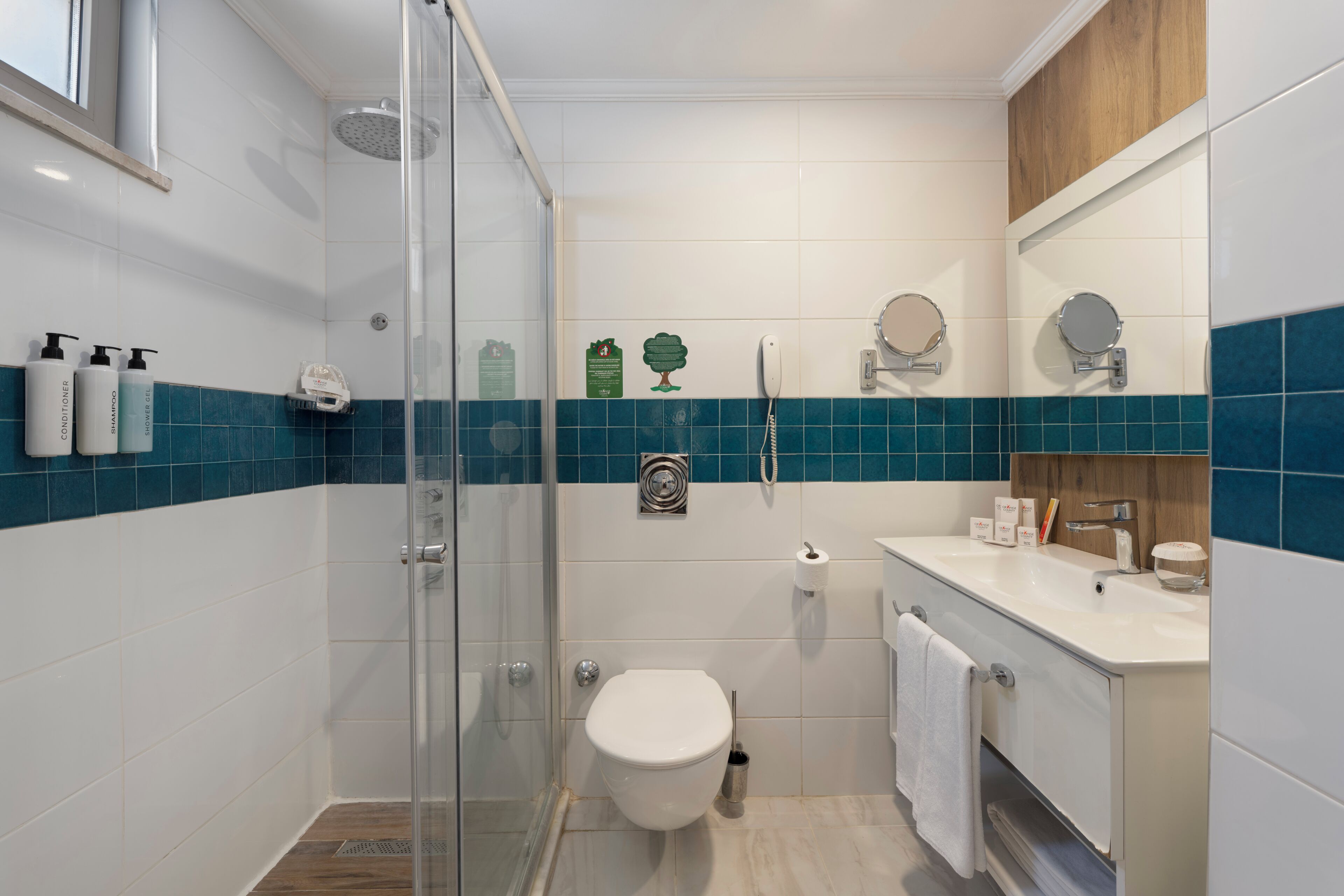 Casa de banho moderna com cabine de duche em vidro, sanita branca e toucador com espelho.
