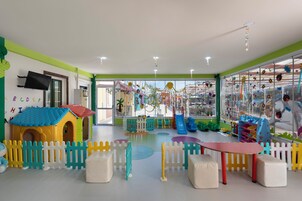 Un área de juegos infantiles con una casita, estructuras recreativas y un tobogán.