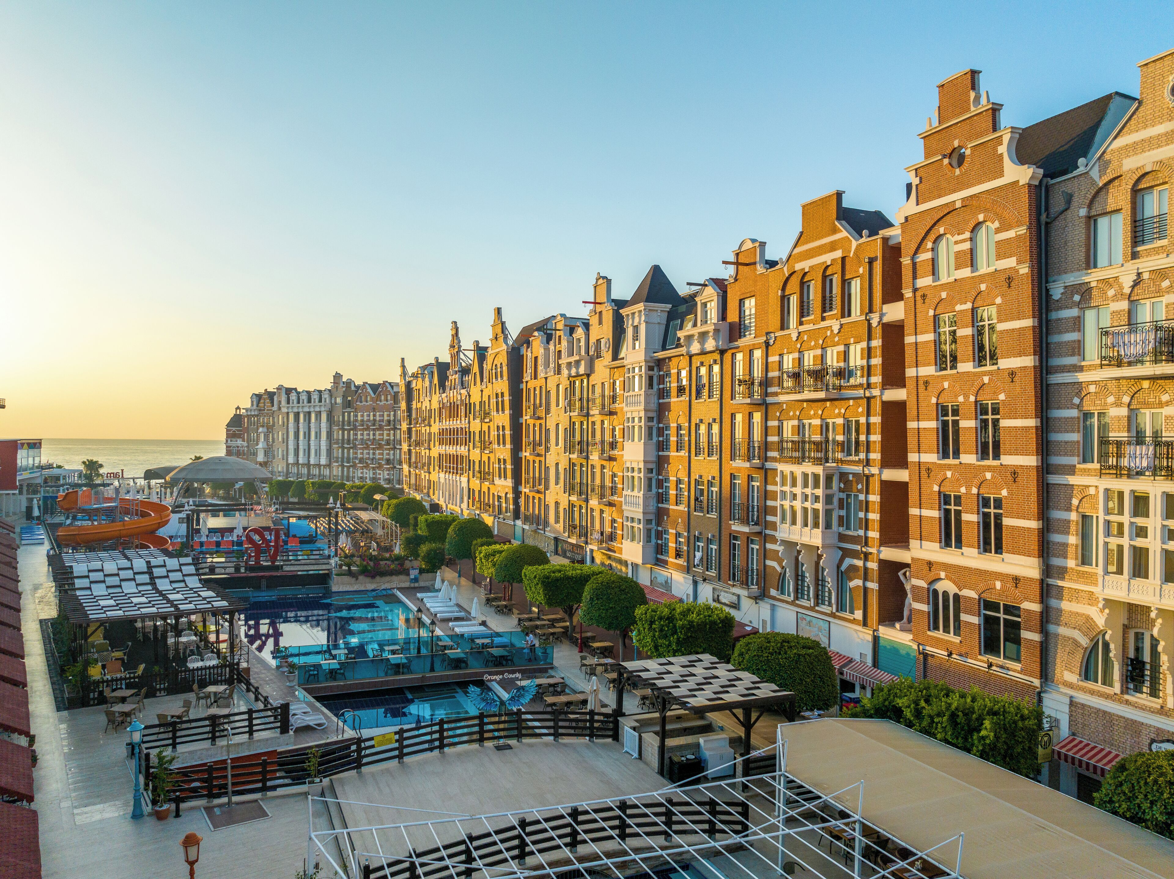 A waterfront hotel with a pool area, outdoor seating, and traditional European architecture.
