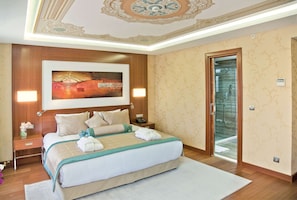 A hotel room with a large bed, a painting above the bed, a nightstand with a lamp, and a bathroom door. - Hurry Inn Merter Istanbul (Istanbul)
