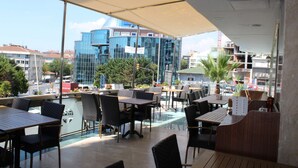 An outdoor seating area with tables and chairs, a view of a modern building, and a clear sky. - Hurry Inn Merter Istanbul (Istanbul)