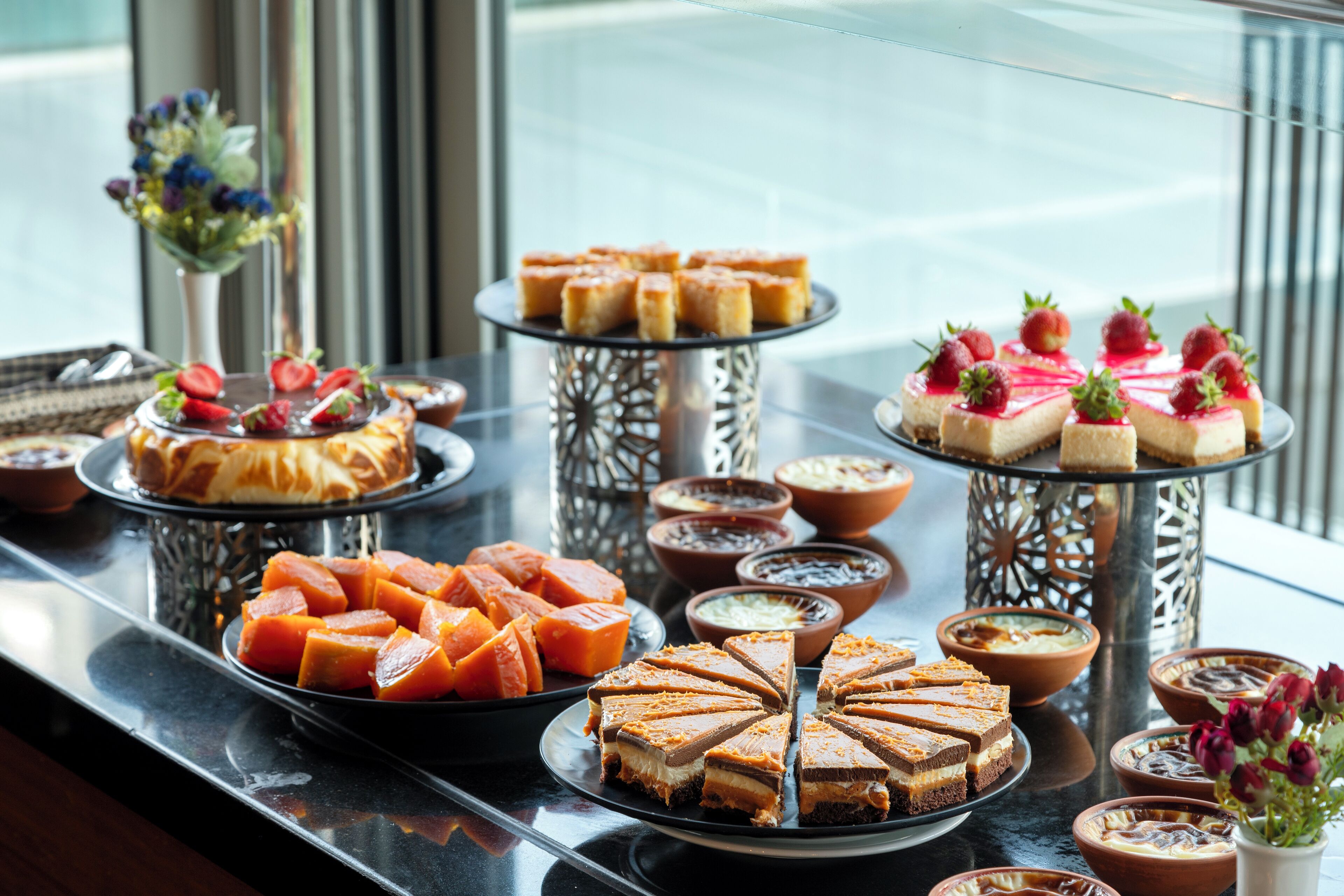 A buffet with various desserts and dishes, including cakes, pastries, and fruit.