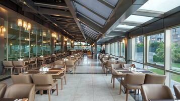 A spacious restaurant with high ceilings, large windows, and modern furnishings.