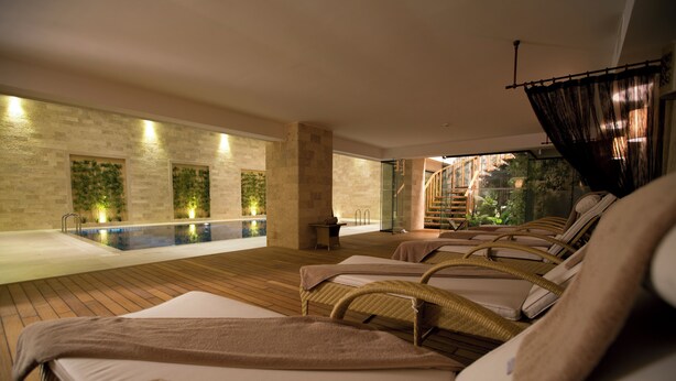 A spa area with a pool, lounge chairs, and a staircase leading to an outdoor area. - Miracle Istanbul Asia Airport Hotel & Spa (Istanbul)
