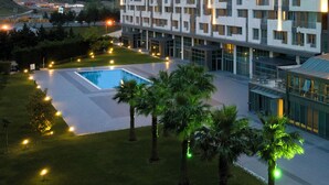 A modern hotel with a pool, surrounded by well-lit pathways and palm trees. - Miracle Istanbul Asia Airport Hotel & Spa (Istanbul)