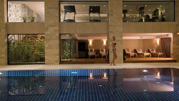 Una piscina cubierta, una piscina al aire libre, sombrillas, tumbonas