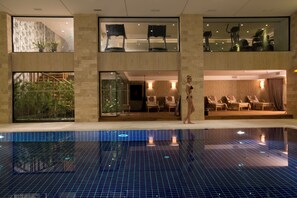 Una piscina techada, una piscina al aire libre, sombrillas