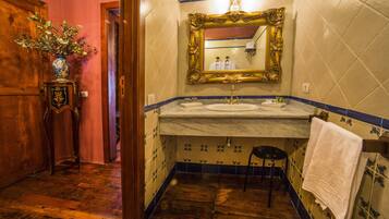 A bathroom with a marble sink, a gold-framed mirror, and a wooden floor.