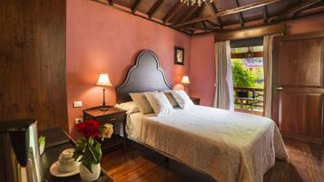 Une chambre à coucher avec un lit, des tables de chevet, des lampes, un lustre, un plafond en bois et une vue sur la verdure à l’extérieur.