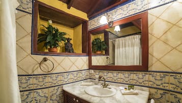 Un baño con lavamanos, espejo, plantas en macetas y cortina de ducha.