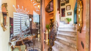 Un interior imponente con una escalera, espejos ornamentados y una araña.