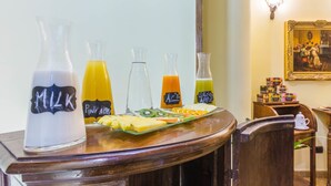 Un bufé de desayuno con bebidas identificadas y una bandeja de frutas.