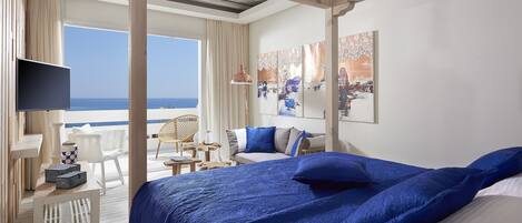 A bedroom with a large bed, a TV, and a view of the sea.