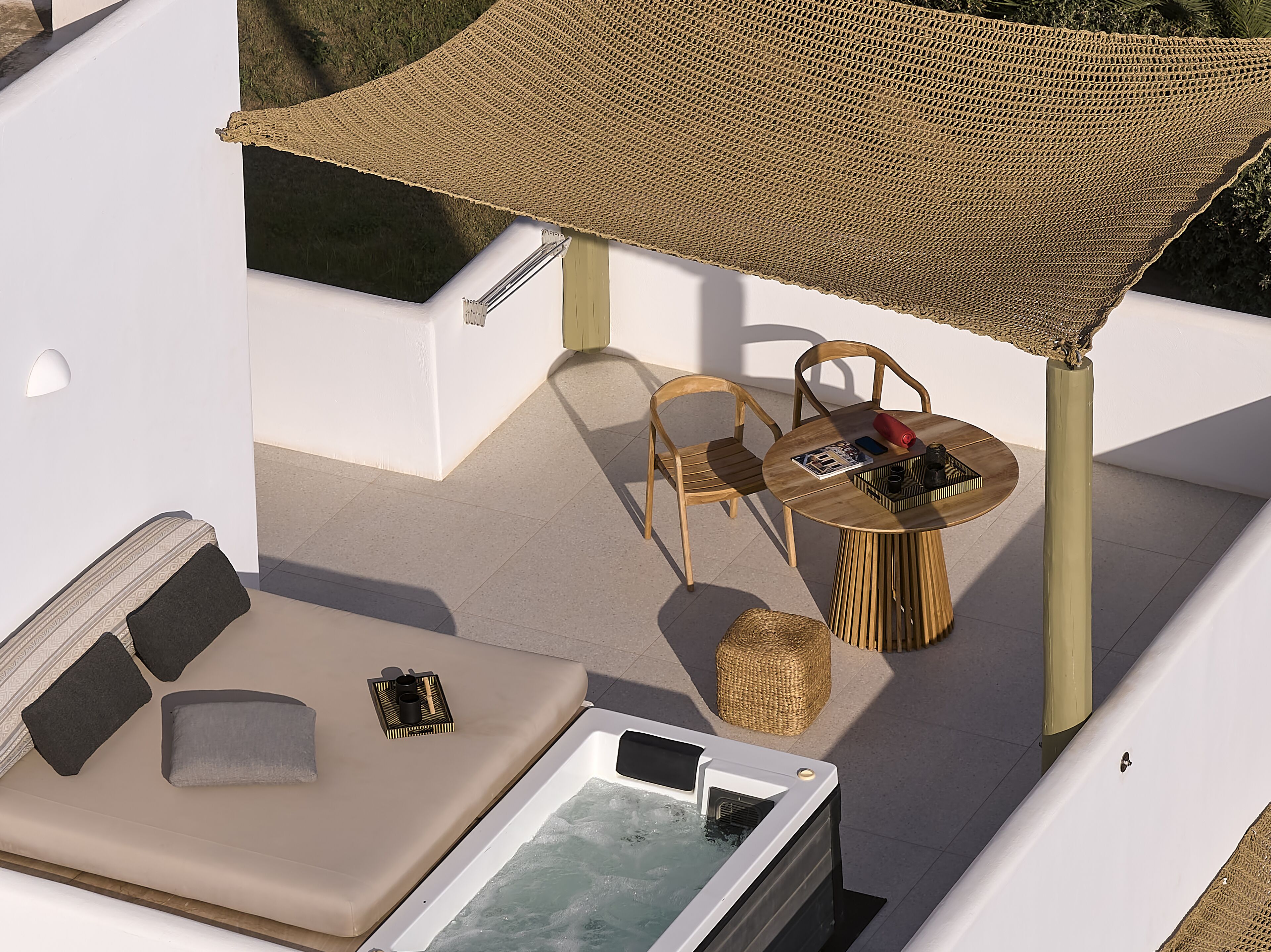 A rooftop terrace with a hot tub, two wooden chairs, a round table with a magazine, and a woven canopy.