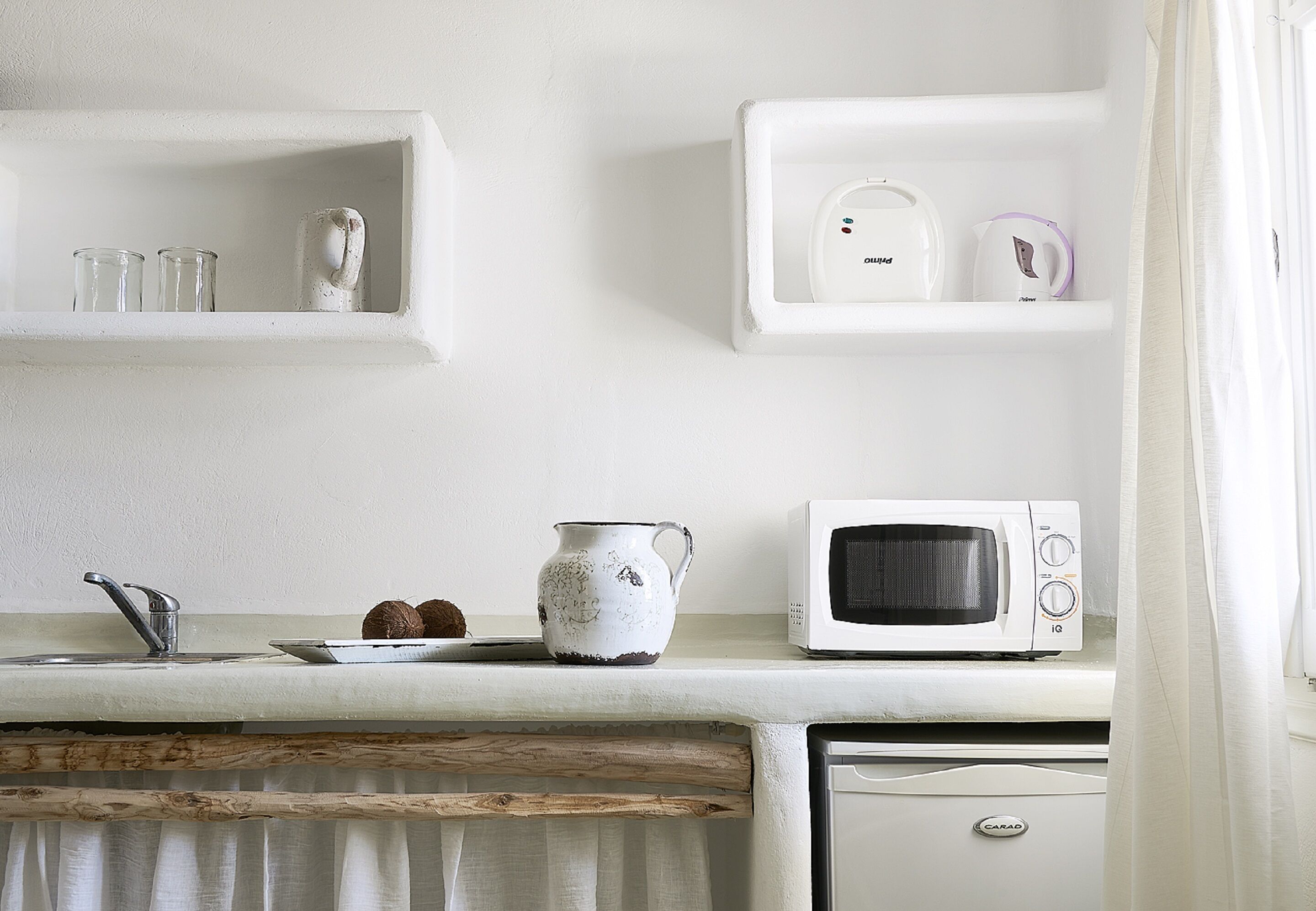 A kitchen with white appliances, a wooden countertop, and a white cabinet.