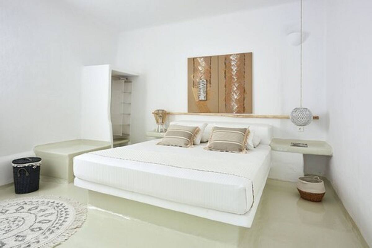 A minimalist bedroom with a bed, bedside tables, a wall-mounted artwork, and a hanging light fixture.
