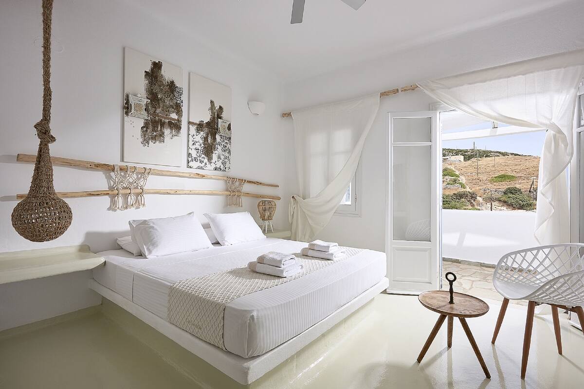 A bedroom with a bed, a chair, a hanging light, and artwork on the wall.