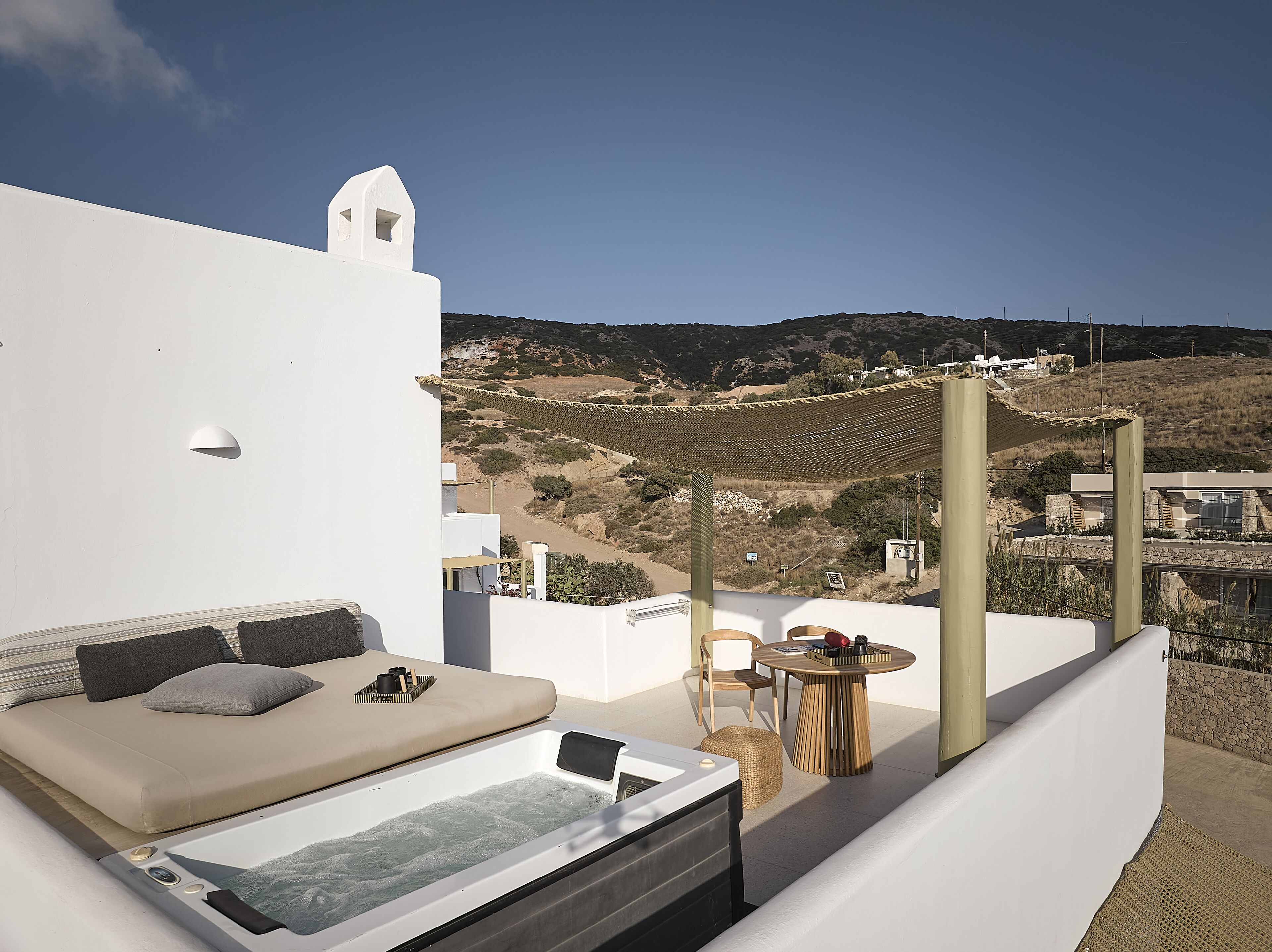 A rooftop terrace with a hot tub, a sofa, and a table with chairs.
