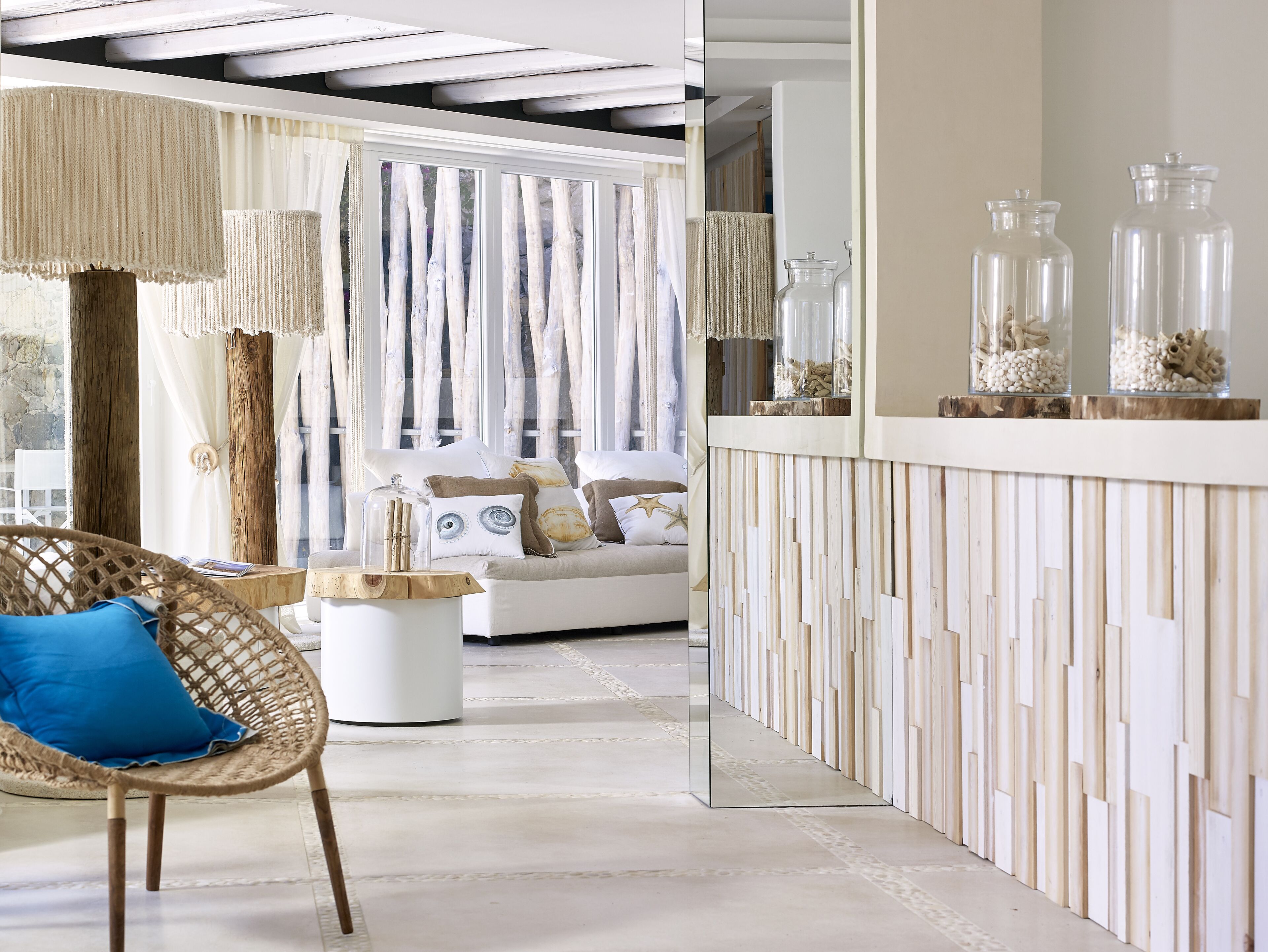 A modern living room with a white sofa, a wicker chair, and a glass coffee table.