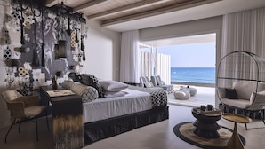 Un dormitorio moderno con cama, mesitas de noche, una lámpara colgante y vistas al océano.
