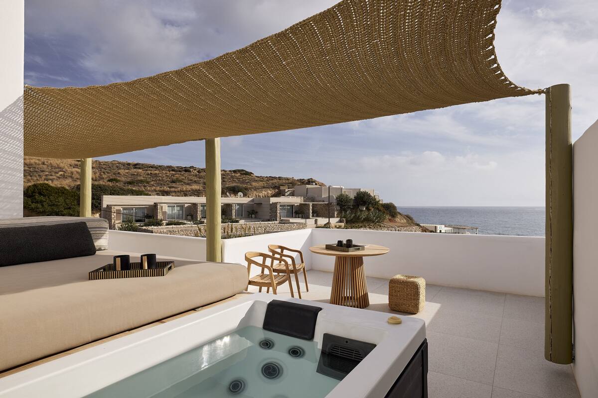 A rooftop terrace with a hot tub, seating area, and a view of the sea.