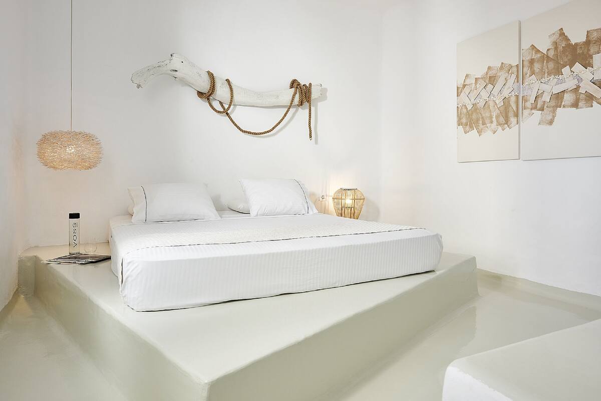 A minimalist bedroom with a bed, bedside table, and wall art.