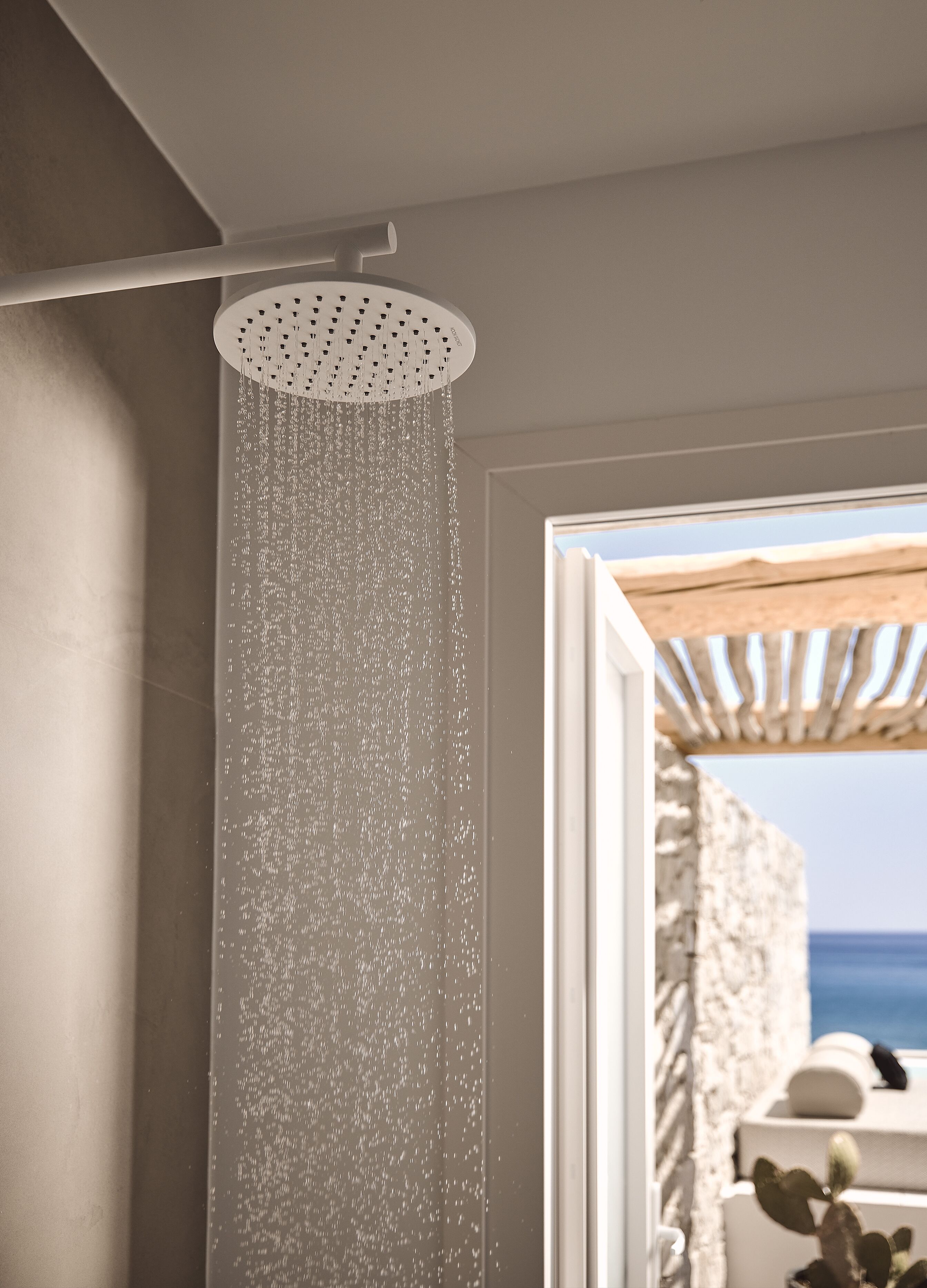 A shower with a circular head and water falling from it.