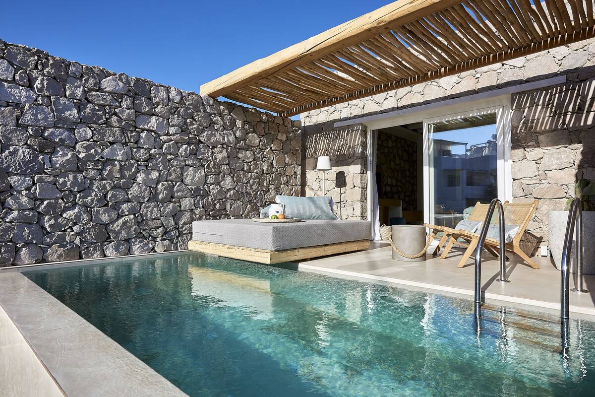 A stone wall, a pool, and a wooden pergola.