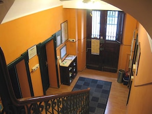 Una escalera con barandilla de madera que lleva a un rellano con un escritorio y una computadora.