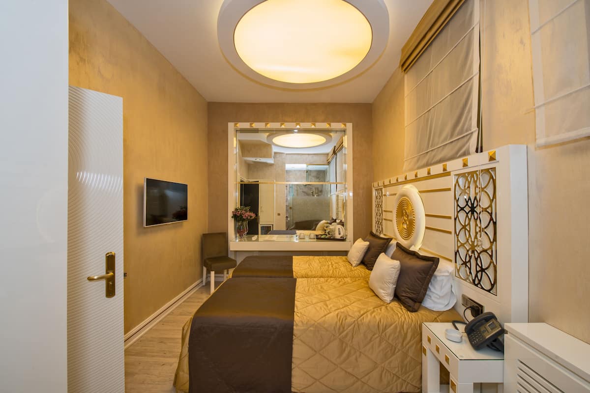 A hotel room with a bed, bedside table, mirror, and a television.