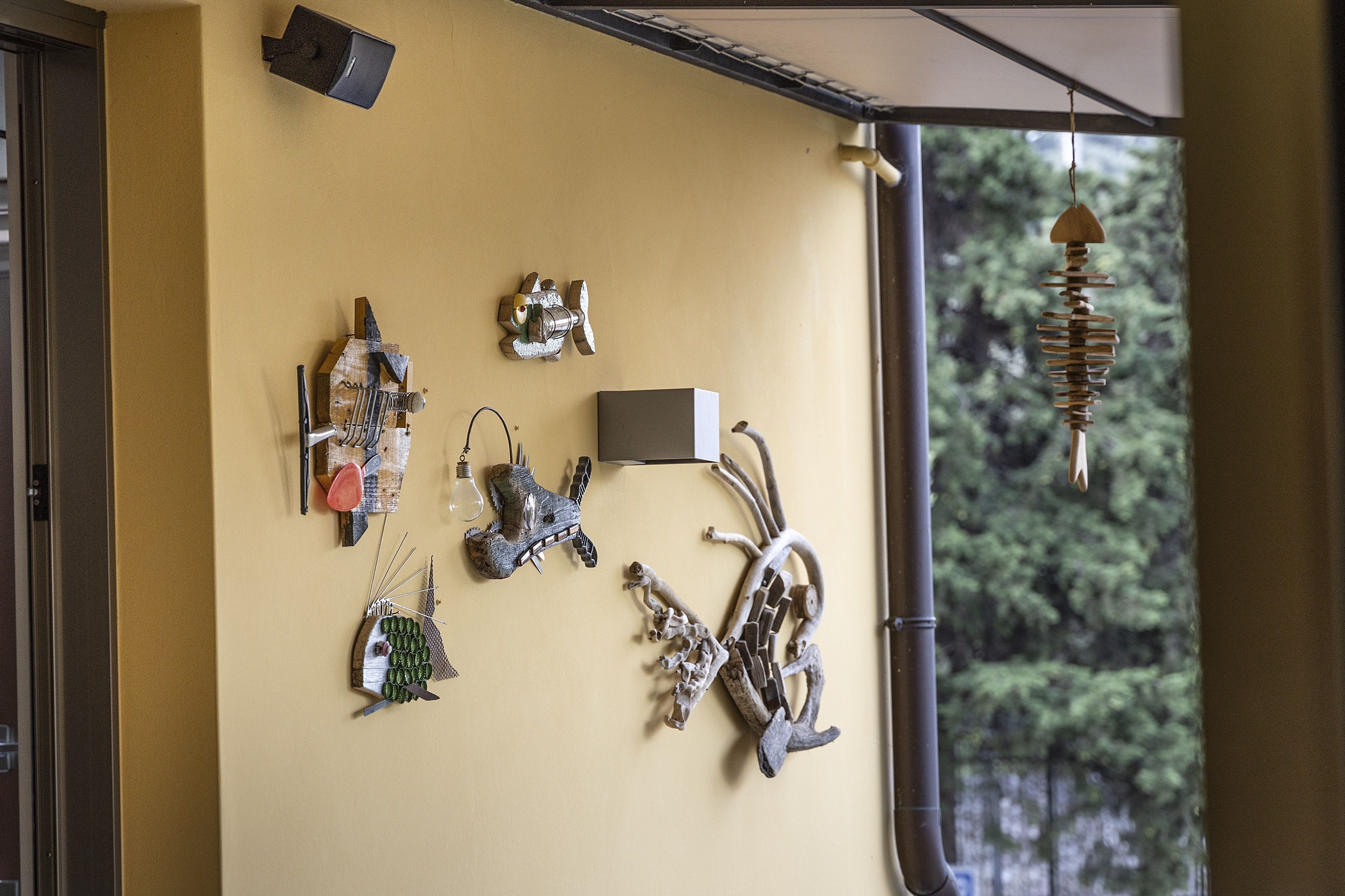Una pared con varias esculturas de metal y un móvil colgante.