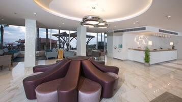A modern lobby with a unique seating arrangement, a reception desk, and large windows offering a view.