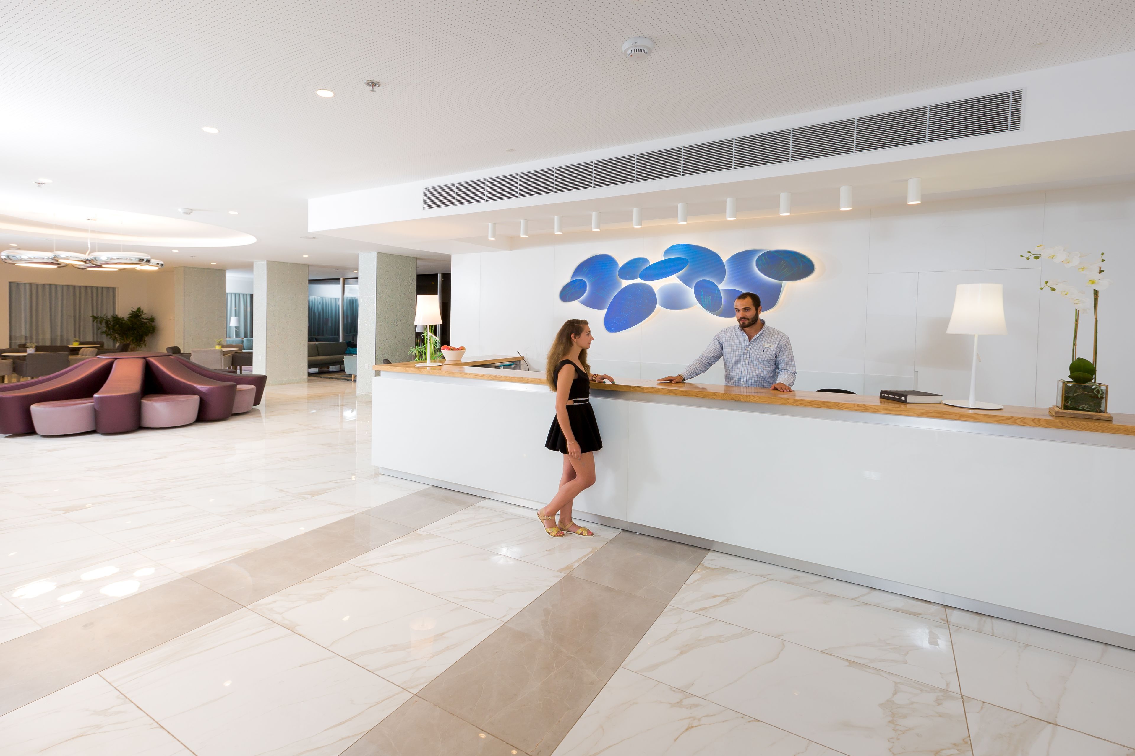 A reception area with a modern design, featuring a reception desk, seating area, and decorative wall art.