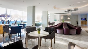 Un moderno vestíbulo de hotel con zona de estar, una recepción y un amplio ventanal con vistas.