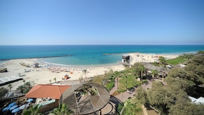 Un resort en la playa con vista despejada al océano, una playa de arena y unas pocas palmeras.