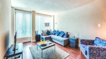 A modern living room with a sectional sofa, a coffee table, and a flat-screen TV.