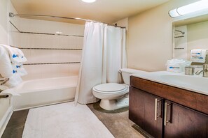 A bathroom with a bathtub, toilet, and vanity.